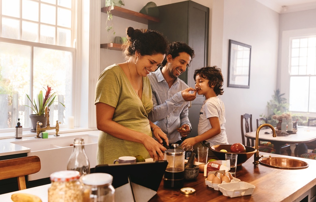 Family standing at a kitchen island sampling food.