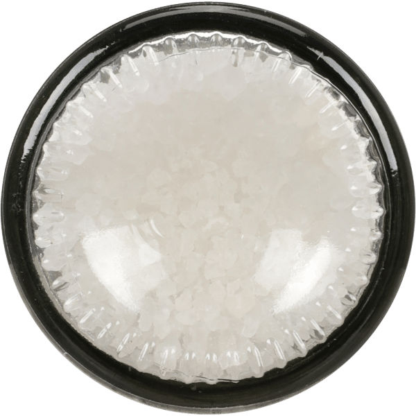 Glass jar filled with coarse white sea salt, viewed from above, highlighting the texture and clarity of the salt crystals. Ideal for culinary uses and seasoning.