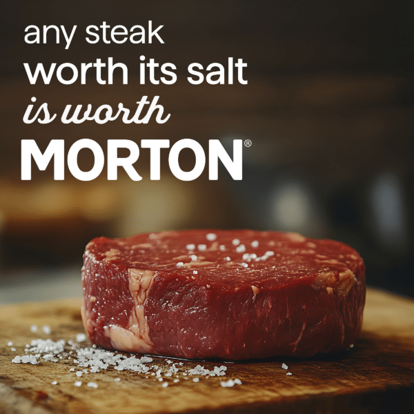 Close-up of a raw steak on a wooden cutting board, sprinkled with coarse salt, emphasizing quality and flavor. The image features the text promoting Morton salt, highlighting its importance for seasoning steak.