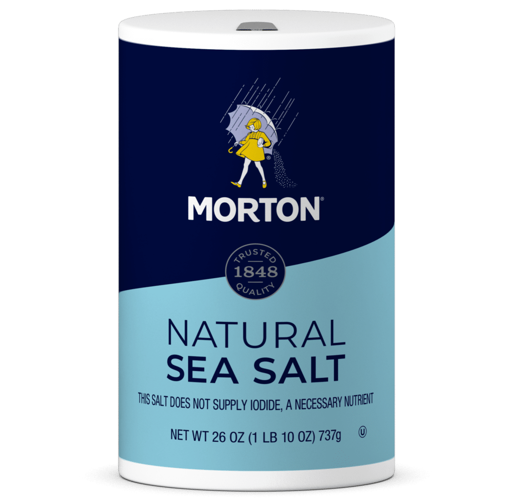 Morton Natural Sea Salt container, 26 oz, featuring a blue and dark blue design with a vintage logo and a warning about lack of iodide, ideal for seasoning and cooking.