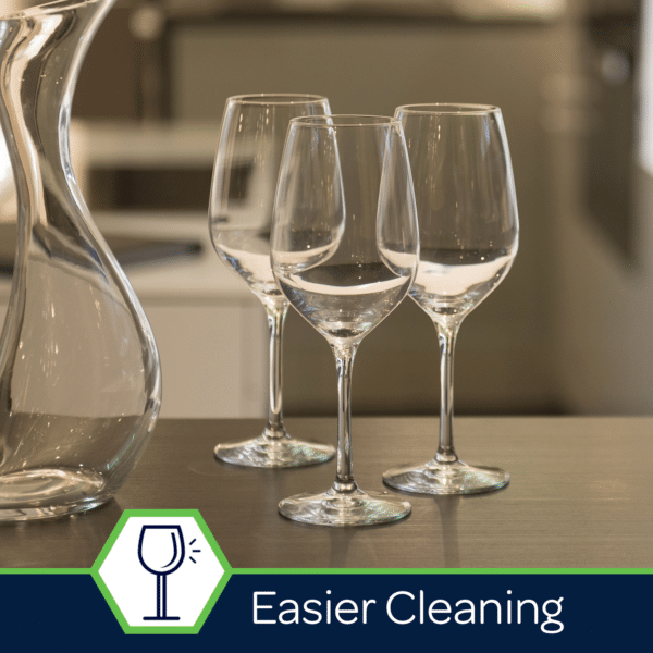 Clear wine glasses positioned elegantly next to a glass decanter on a modern table, highlighting the theme of easier cleaning for kitchenware.