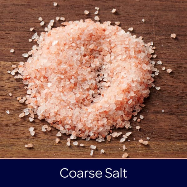 Coarse salt piled on a wooden surface, showcasing its pink and white crystalline texture, ideal for seasoning and cooking.
