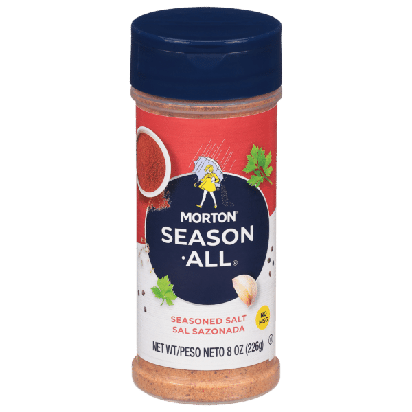 Morton Season-All seasoned salt container, 8 oz, featuring a red label with a cartoon character and herbs, emphasizing no MSG. Ideal for enhancing the flavor of various dishes.