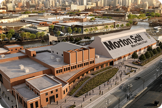Aerial view of the Morton Salt building, showcasing its distinctive architecture and modern design, surrounded by urban landscape and greenery, with people walking along the pathway.