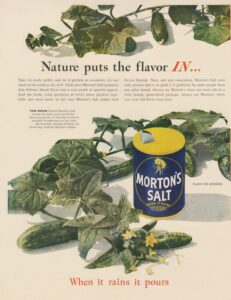 Vintage advertisement for Morton's Salt featuring cucumbers and garden leaves, emphasizing how salt enhances flavor in vegetables. The can displays the slogan "When it rains it pours," highlighting the product's convenience and appeal for cooking and preserving food.