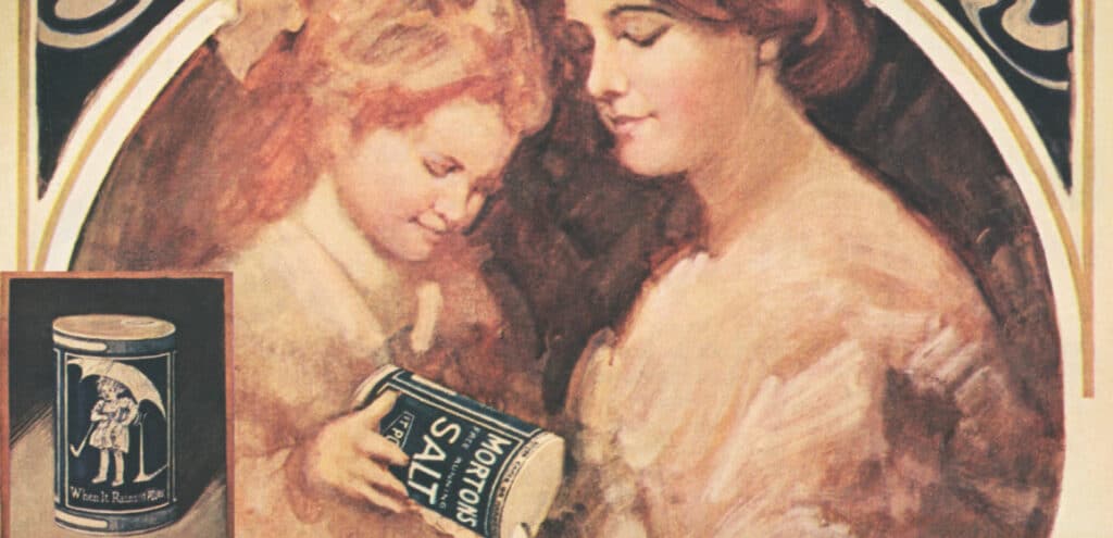 Vintage advertisement featuring a woman and a girl admiring a can of Morton's Salt, showcasing classic branding and nostalgic imagery. The inset highlights the iconic packaging design, emphasizing the product's historical significance in culinary culture.