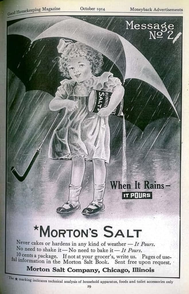 Vintage advertisement for Morton Salt from Good Housekeeping magazine, October 1914. Features a young girl with curly hair holding a can of salt under an umbrella, illustrating the slogan "When It Rains, It Pours." Highlights the product's ability to pour easily in any weather without clumping.