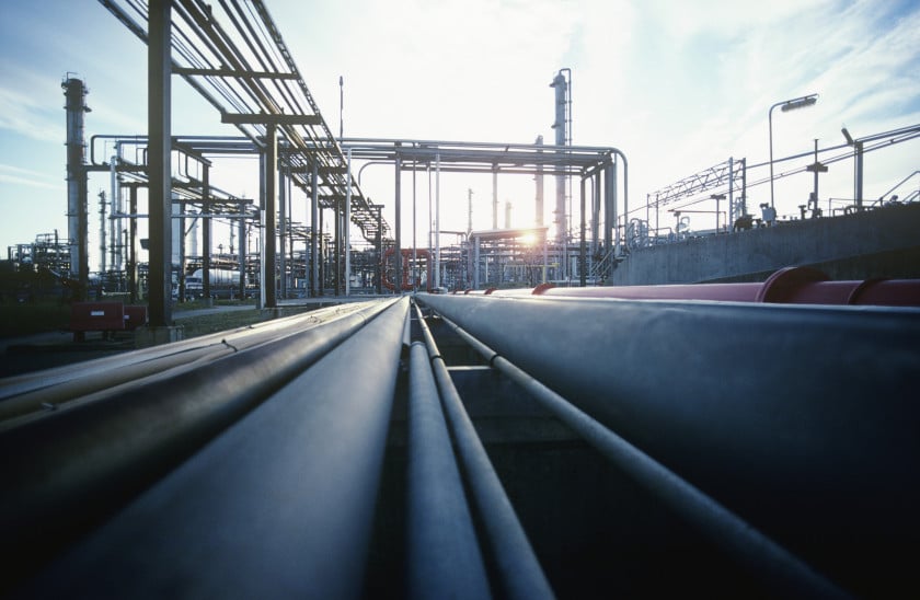 Industrial pipeline network at a petroleum refinery, showcasing metal pipes and structures against a sunset backdrop, highlighting energy infrastructure and manufacturing processes.