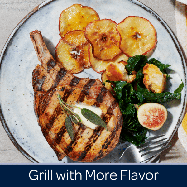 Grilled pork chop served with sautéed kale, crispy apple slices, and a fresh fig on a rustic plate, showcasing a delicious and flavorful meal.