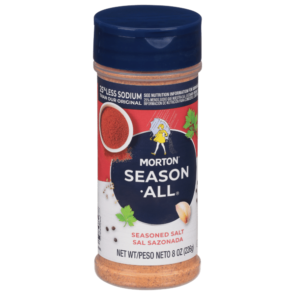 Morton Season-All seasoned salt container, 8 oz, featuring a blue lid and nutritional information highlighting 25% less sodium than the original. The label includes images of spices and herbs, emphasizing its flavor-enhancing qualities for various dishes.