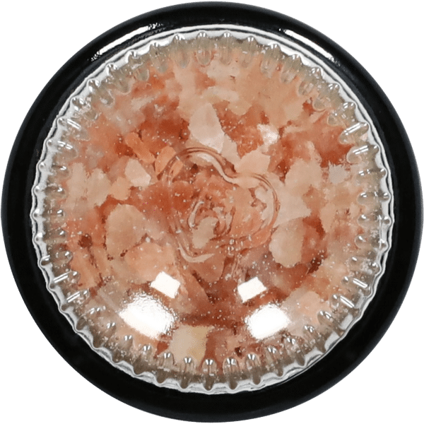Close-up view of a glass container filled with pink Himalayan salt crystals, showcasing the coarse texture and natural color variations, ideal for culinary use and wellness applications.