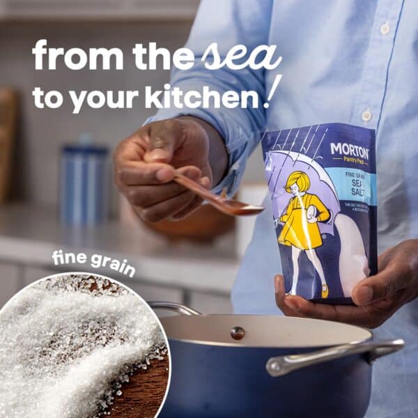 Image of a person measuring fine grain sea salt from a Morton Pantry Pack into a cooking pot, highlighting the journey of sea salt from the ocean to home kitchens. The image emphasizes the quality and versatility of this essential cooking ingredient.