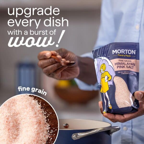 Person adding Morton fine grain Himalayan pink salt to a pot, showcasing the product packaging and a close-up of the salt texture. Ideal for enhancing flavors in cooking.