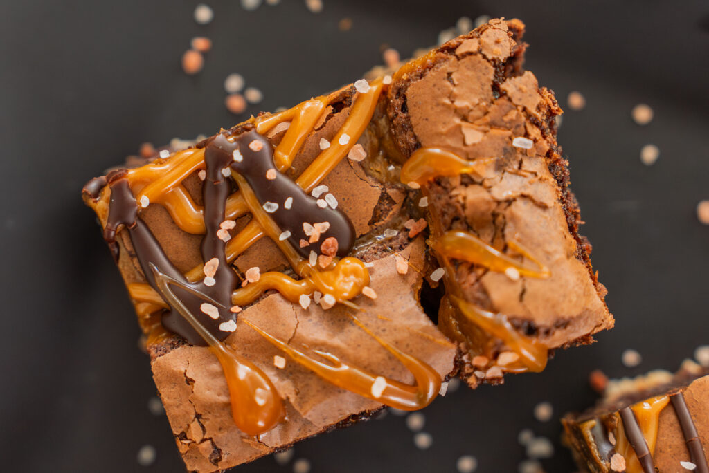 Decadent chocolate brownies drizzled with caramel and dark chocolate, topped with a sprinkle of sea salt for added flavor. Perfect for dessert lovers seeking a sweet treat.